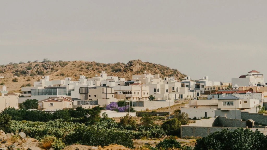 Casas en la ladera y árboles verdes en Taif con montañas detrás, cerca del teleférico de Al Hada
