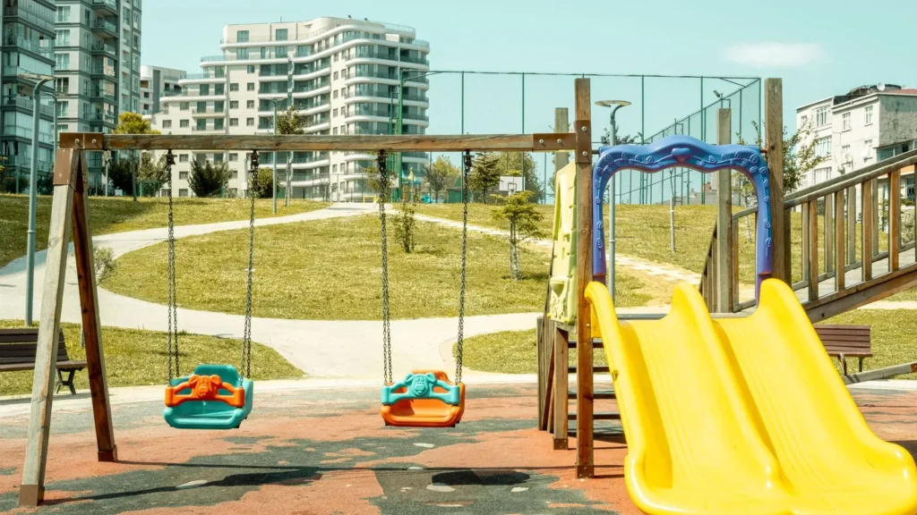 Parque infantil con columpios y un tobogán amarillo en un parque urbano, el tipo de parada que encaja en un día en Yeda con niños