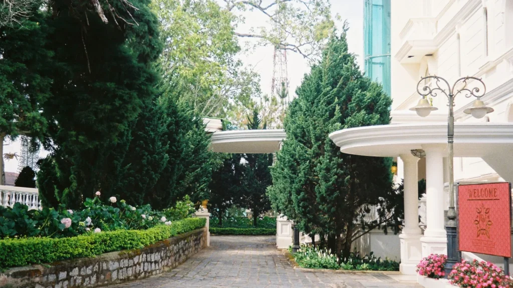 Entrada de hotel con zona cubierta para coches, árboles y parterres de flores, el punto de partida al cambiar de hotel en Taif