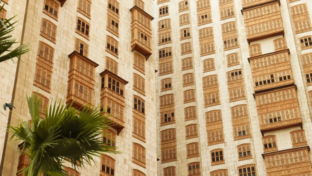 Edificio alto con celosías tradicionales de madera en las ventanas y palmeras, escenario de una visita guiada por Al Balad