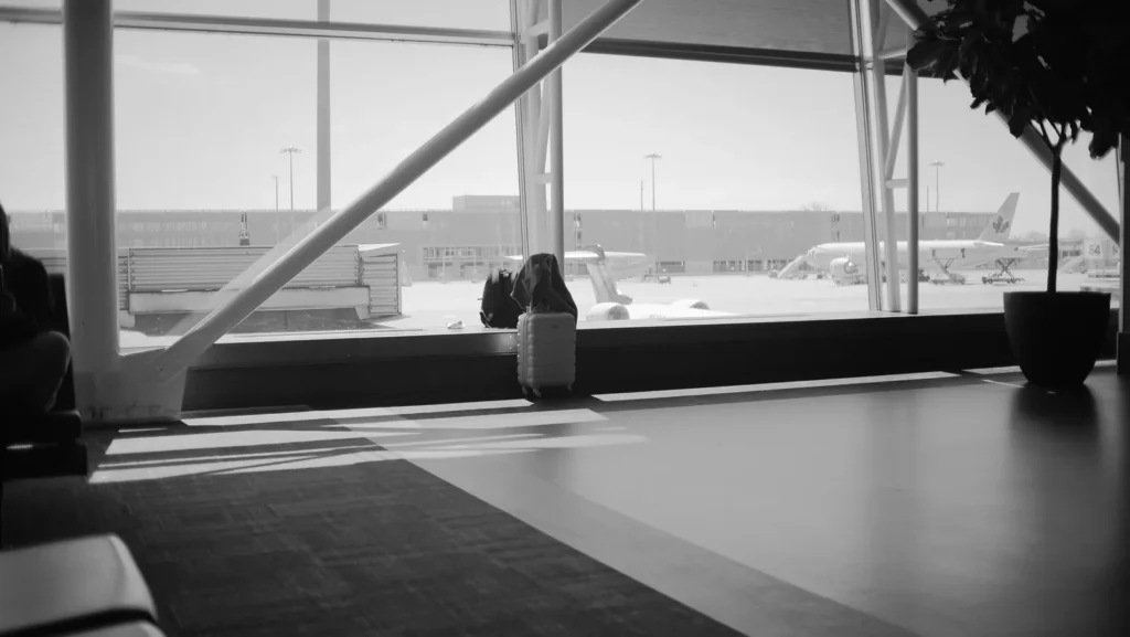 Una maleta junto a la ventana de un aeropuerto con vistas a los aviones en la plataforma, como recordatorio de qué hacer con una maleta perdida en el aeropuerto de Yeda