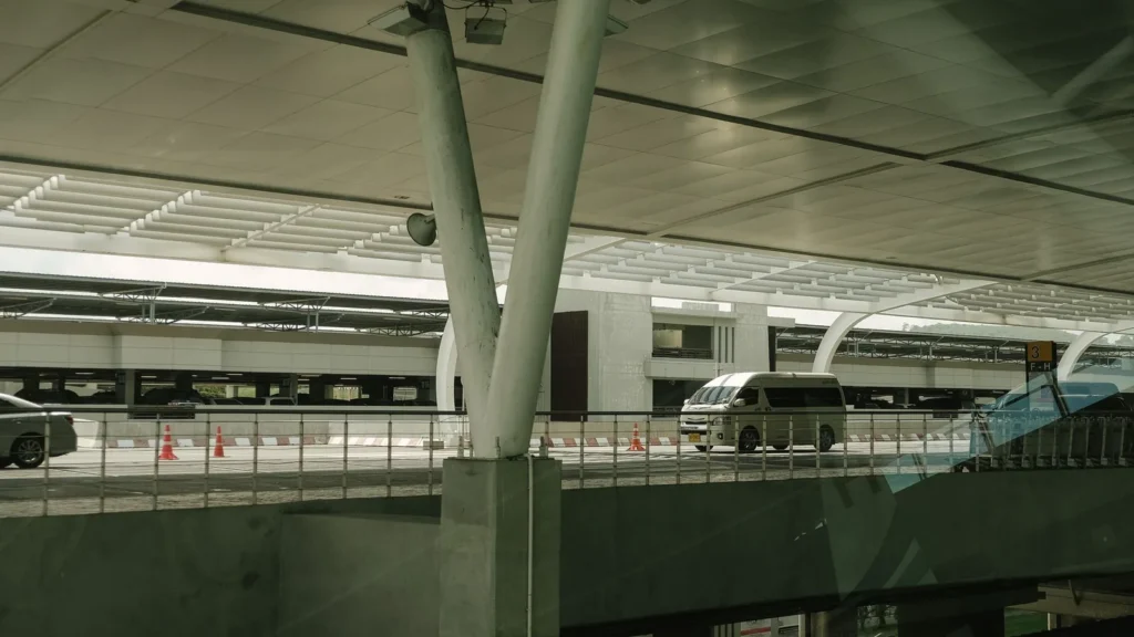 White passenger van on the road outside a modern terminal building