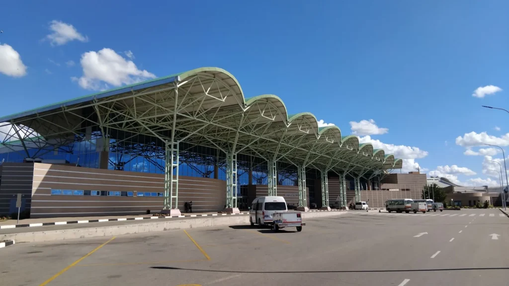 Modern airport terminal exterior with cars and taxis at the kerb under a clear blue sky