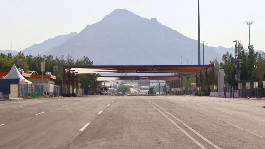 Wide empty highway leading towards a mountain under a clear sky