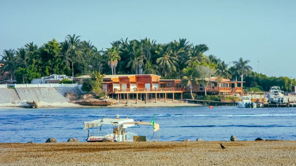 Palmengesäumtes Ufer und ein kleines Boot an einem der Strände in Jeddah an einem klaren Tag
