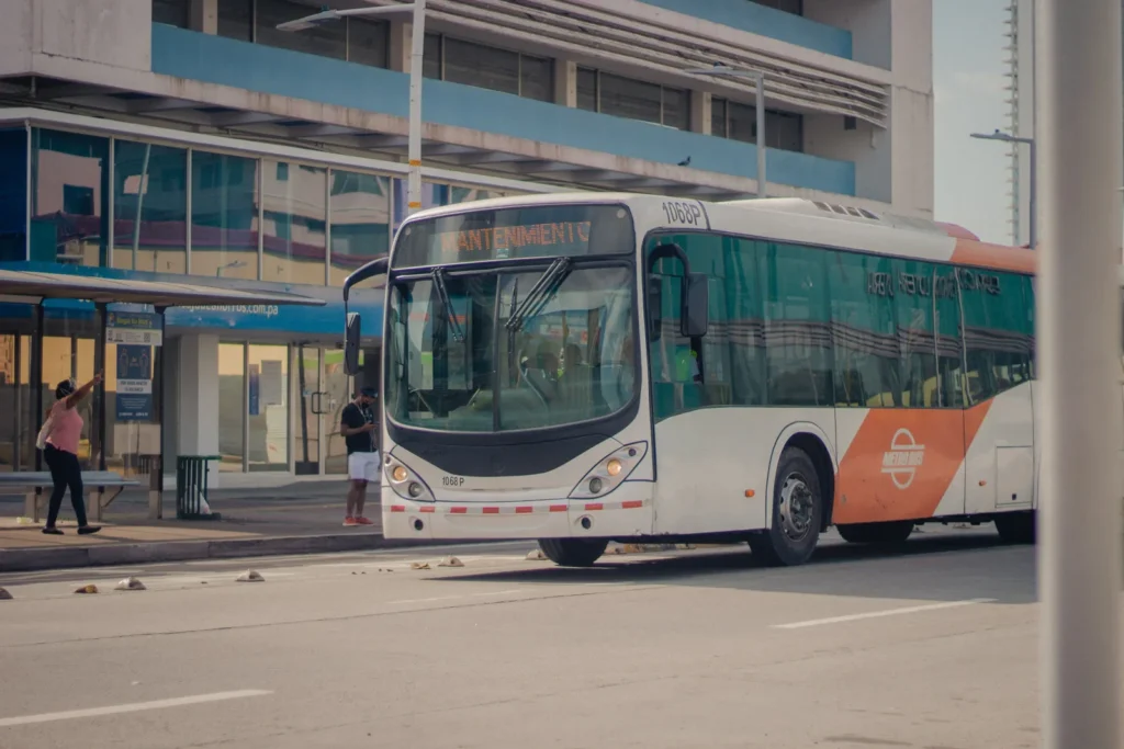 Weiß-oranger Stadtbus neben einer überdachten Haltestelle, Symbolbild für öffentliche Verkehrsmittel in Jeddah