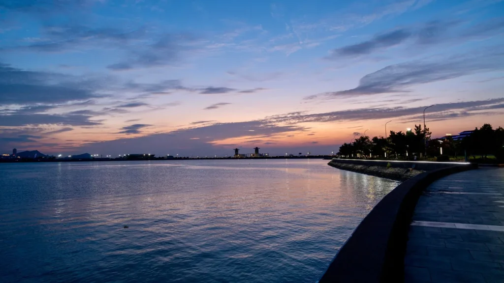 Ruhiges Meer und Uferpromenade bei Sonnenuntergang mit Stadtlichtern in der Ferne – Abendstation für Jeddah Sehenswürdigkeiten an einem Tag
