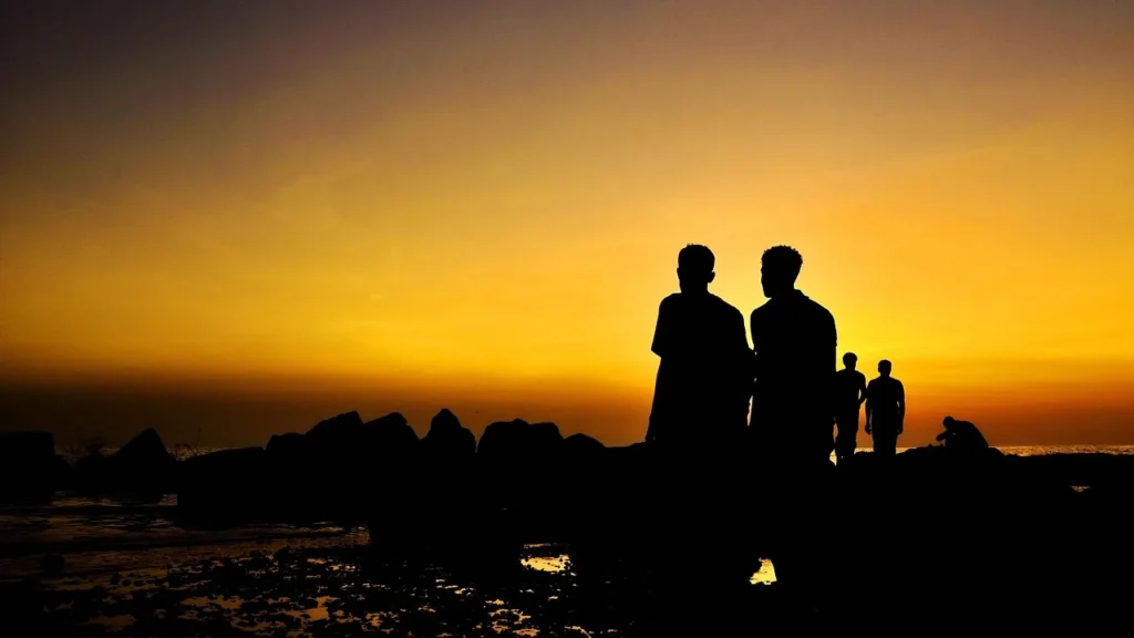 Silhouetten einer Familie, die abends an der Küste von Jeddah den Sonnenuntergang über dem Meer betrachtet – Auftakt für den Jeddah Season Transport