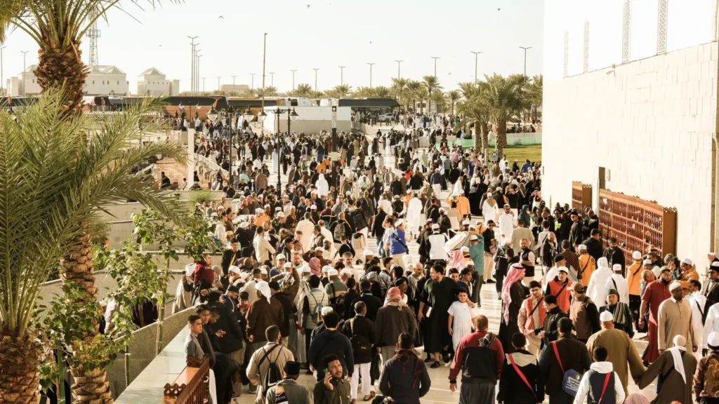 Gran multitud caminando al aire libre en un recinto concurrido de Arabia Saudí, a la salida de un evento al que se llega en taxi al Jeddah Superdome