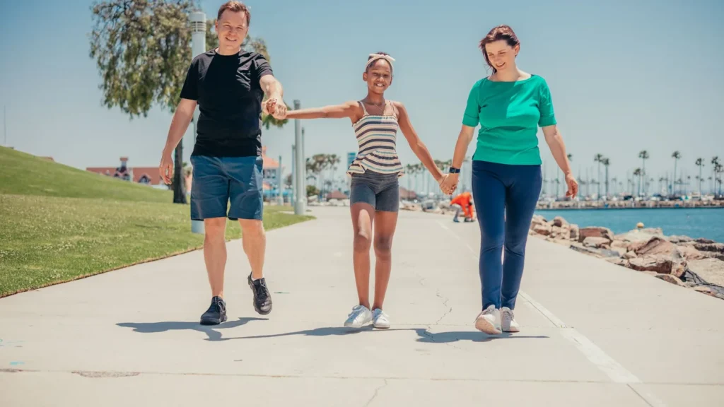 Family of three walking hand in hand along a seafront path