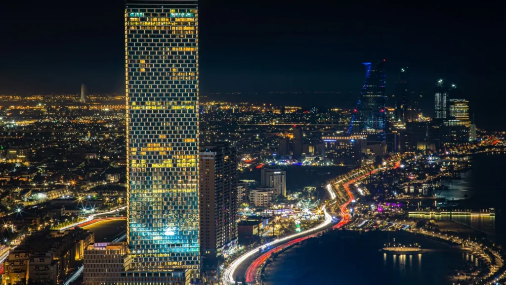 Skyline von Jeddah bei Nacht mit beleuchtetem Turm und Verkehr an der Küste – Abholung nach einer Veranstaltung in Jeddah