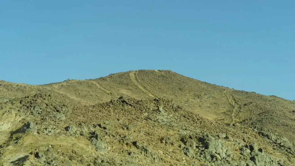 Laderas de montaña escarpadas, entre verdes y pardas, bajo un cielo despejado en las tierras altas saudíes, donde se reparte lo que hay que ver en Taif