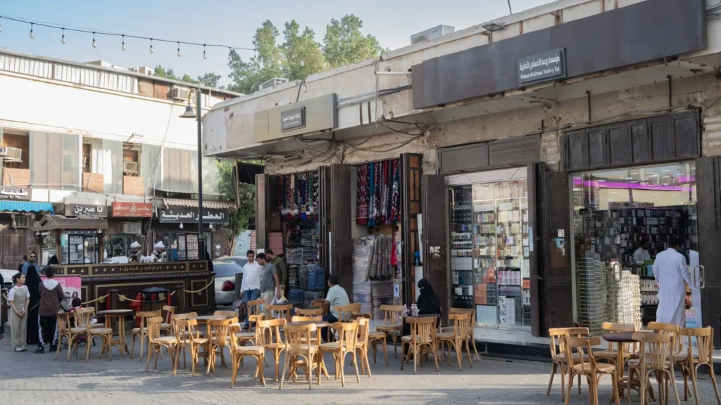 Calle de tiendas con terrazas de café en un mercado de Oriente Medio, ideal para ir de compras en Yeda en taxi