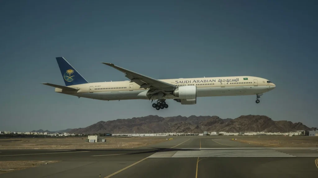 Un Boeing 777 de Saudia aterrizando en una pista con montañas al fondo, al final del taxi de Taif al aeropuerto de Yeda