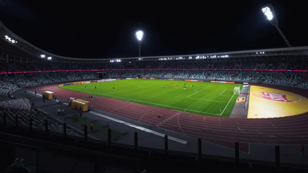 Estadio de fútbol con los focos encendidos de noche, el césped y las gradas vacíos: el destino de un taxi al estadio Rey Abdalá