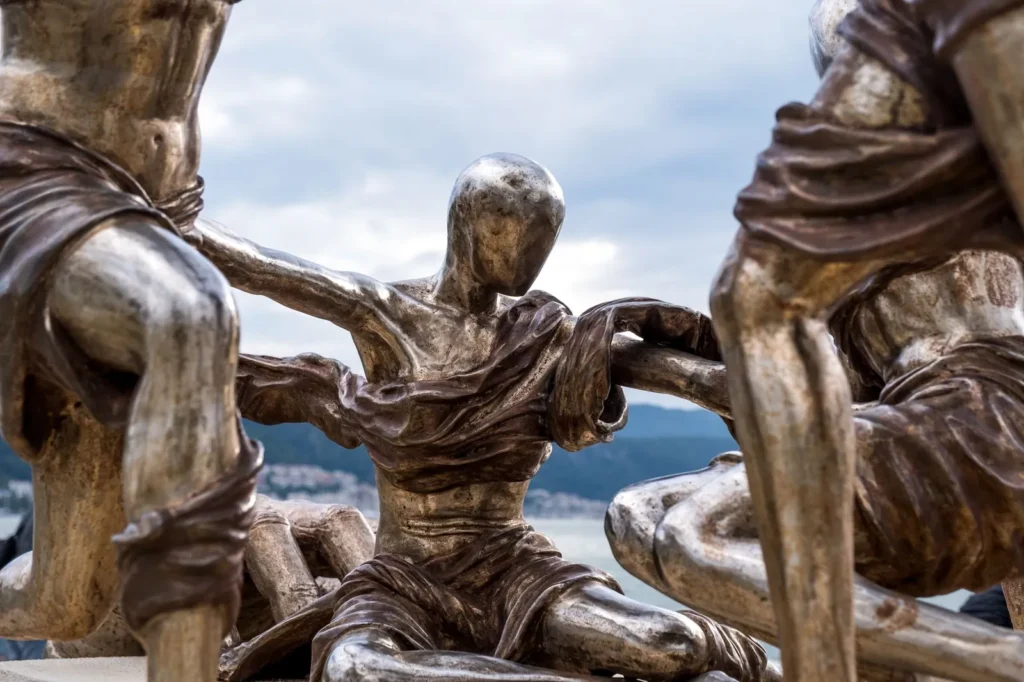 Bronze sculptures of human figures with the sea and sky behind them
